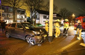 Personenauto na rit over trottoir en klapband tegen mast bovenleiding Broekmolenweg Rijswijk