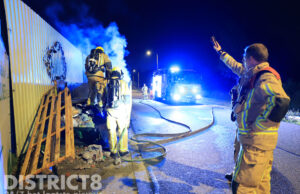 Brandweer blust felle containerbrand tegen hekwerk van scheepswerf Rotterdamseweg Delft