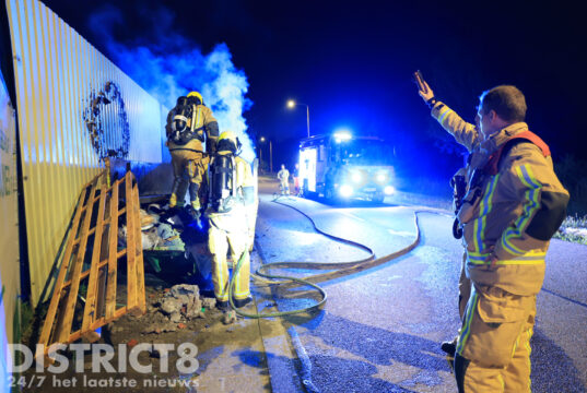 Brandweer blust felle containerbrand tegen hekwerk van scheepswerf Rotterdamseweg Delft