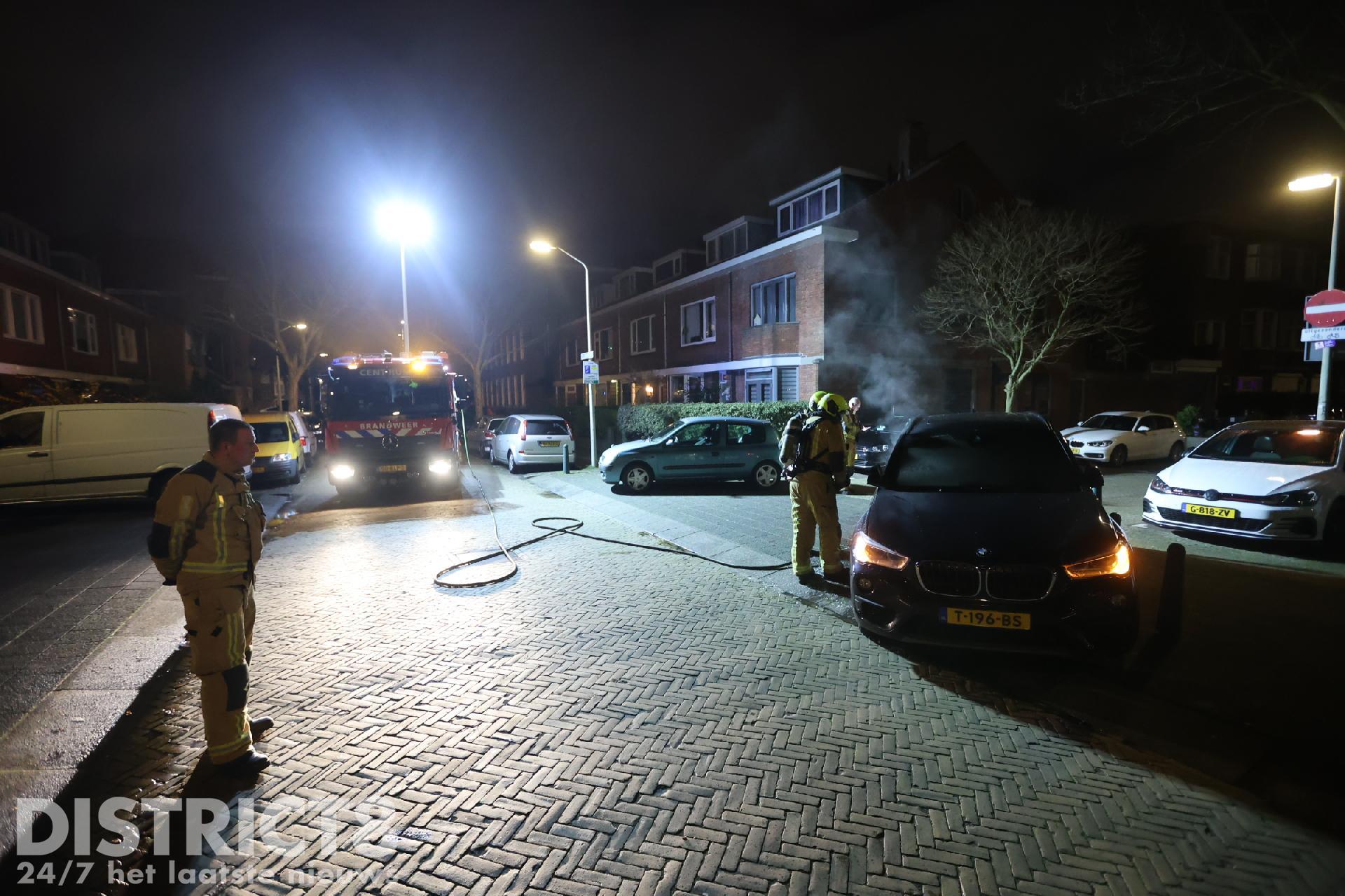 Brandweerlieden blussen een autobrand;  vermeende brandstichting Ellekomstraat Den Haag