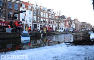 Auto glijdt van brug Delftse gracht in, omstanders springen er achter aan Kolk Delft
