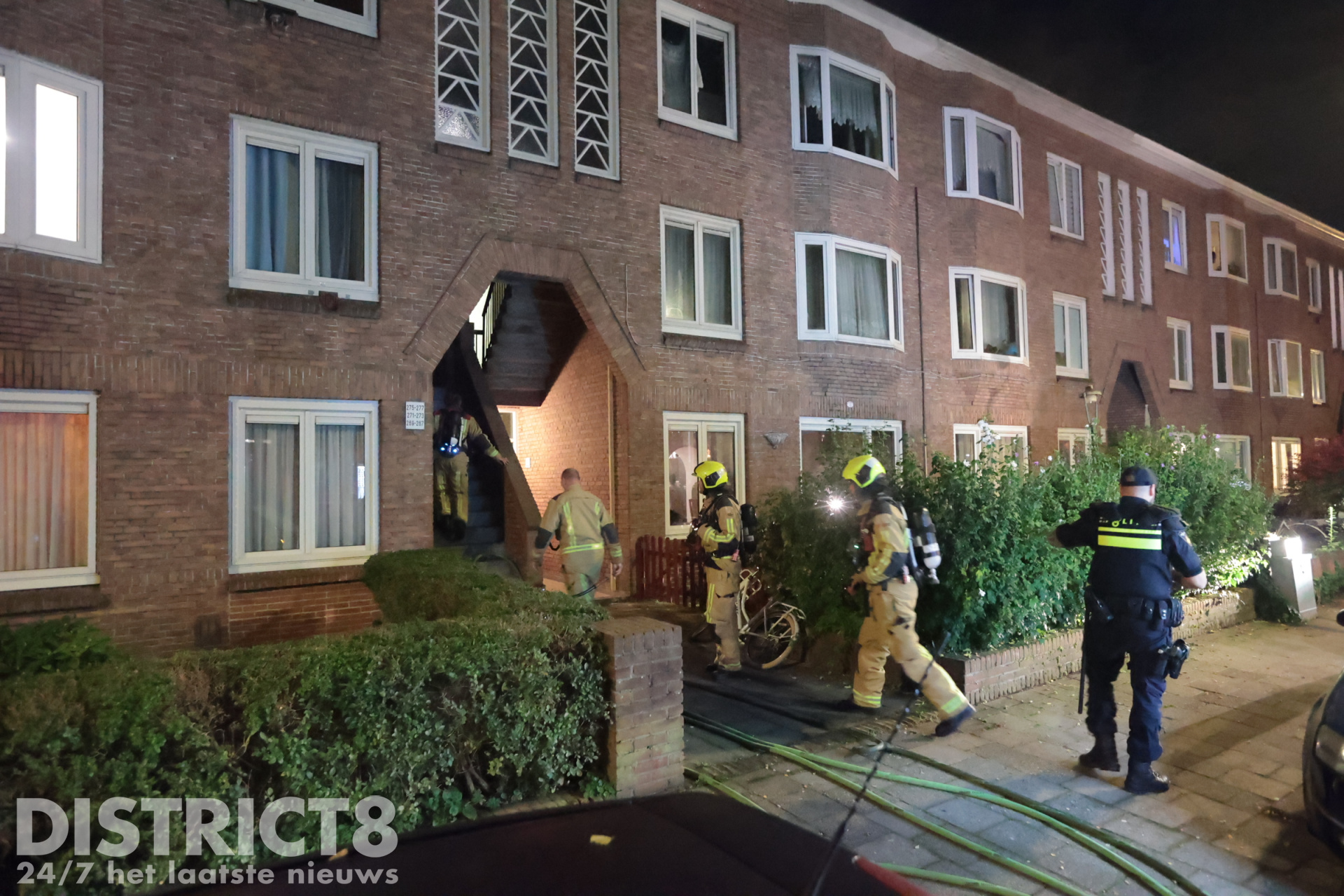 Brandweerlieden bestrijden de brand in het portiek van de woning Drebbelstraat Den Haag