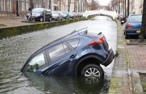 Auto rolt Delftse gracht in Voorstraat Delft