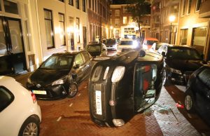 Auto op z’n kant in smalle straat na aanrijding Willemstraat Den Haag