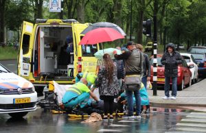 Voorbijgangers staan paraplu af om aangereden vrouw te helpen Beresteinlaan Den Haag