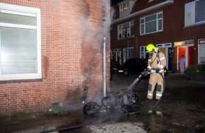 Scooter in brand tegen gevel van woning Boylestraat Schiedam